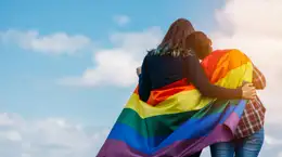 Two people wearing the PRIDE flag