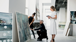 Three people evaluating a painting