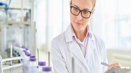A researcher making notes in a lab