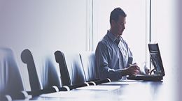 A person working on laptop on a conference table