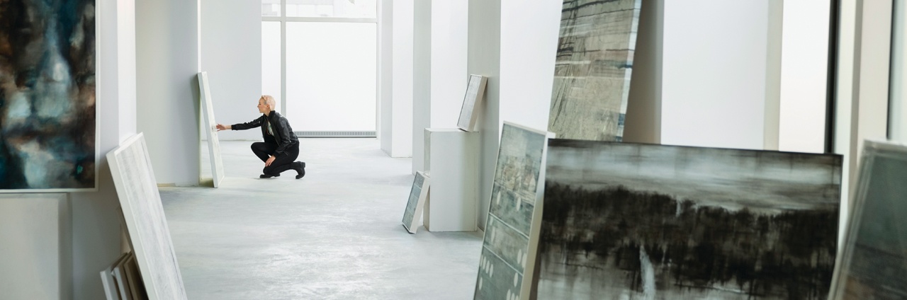 An art gallery with a visitor looking at a painting closely