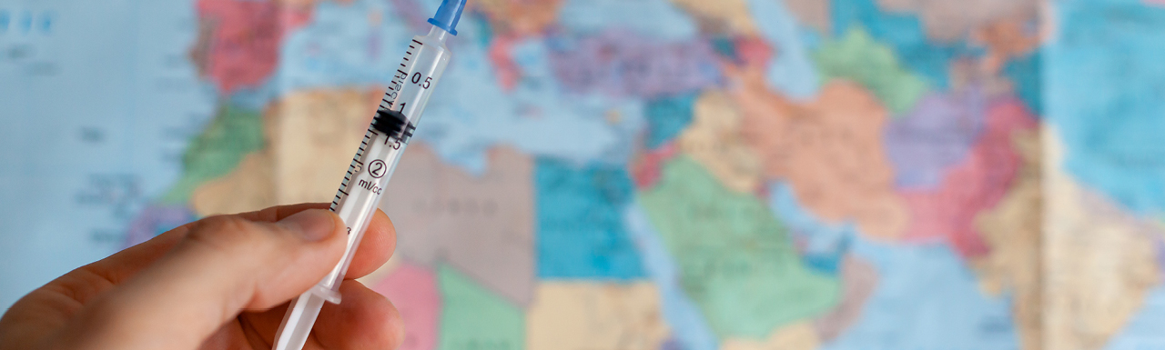 A syringe in front of a world map 