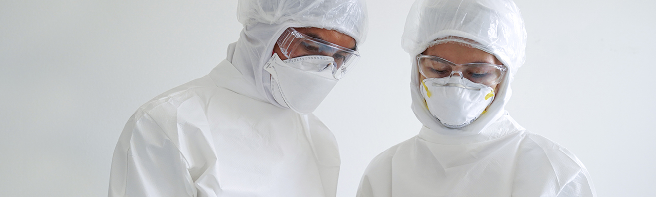 Two researchers working and looking down in their protective gear