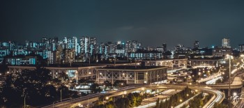 A city in the evening with all buildings lit up and traffic passing through