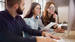 Three colleagues working together and looking at a screen in front